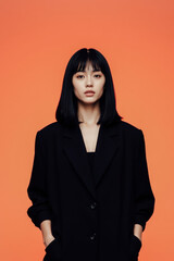Fototapeta premium Stylish Woman in Black Blazer with Orange Background