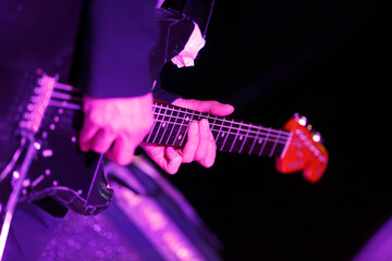 Obraz premium Musician performing on stage with electric guitar during a live concert in the evening under colorful lights