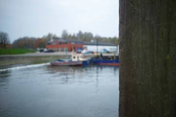 Boats moored at a harbor during a cloudy day near a riverside park in autumn