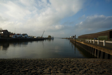 Calm waters reflect the cloudy sky along the quiet harbor in the late afternoon