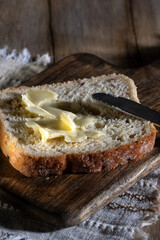 Sliced ​​piece of white bread with butter spread on a rustic table