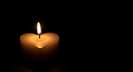 Heart-shaped candle glowing softly in darkness conveying warmth and compassion symbolizing hope and reflection during moments of charity