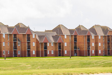 Obraz premium Low rise brick apartment block alongside a park in England on a cloudy summer day