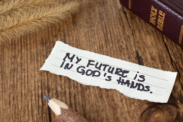 My future is in God's hands, inspirational handwritten quote with holy bible book on wooden table....