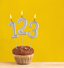 Chocolate cupcake with number 123 candle - Birthday on a yellow background