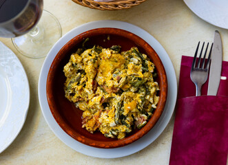 Appetizing scrambled eggs with fried ham and green beans served on platter