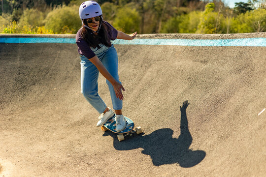 Latin woman practicing surfskate in pump track during sunny day