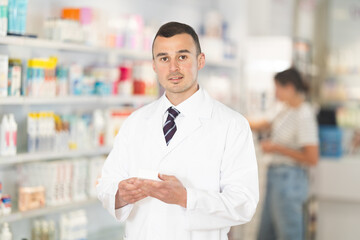 Fototapeta premium Young male pharmacist worker in uniform posing in pharmacy