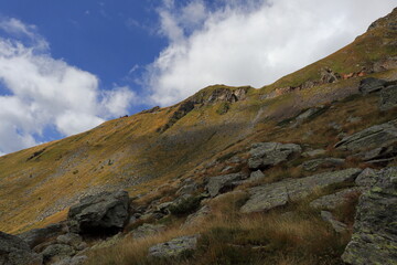 Rocky mountain landscape with golden autumn grass and rugged slope. Natural highland terrain in remote outdoor environment, ideal for hiking and exploration