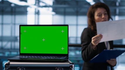 Green screen laptop used by data center admins in blurry background reviewing equipment...