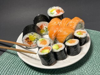 Close-up of a fresh salmon sushi roll served with ginger and wasabi on a sleek white plate