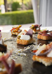 Gourmet finger food. Canapes. Closeup view of a mediterranean bruschetta with different ingredients such as cheese, ham and vegetables, presented in a black board