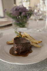Gourmet gastronomy. Wedding main course. Closeup view of grilled loin tournedo with a red wine sauce and potatoes on the table with a beautiful glassware and tableware arrangement