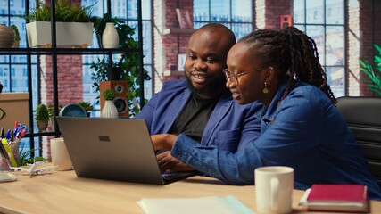 Young couple doing teamwork and multitasking on laptop at desk, fully connected to the internet...