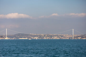 Fototapeta premium A bosphorus bridge spans the width of a body of water, with a city in the background