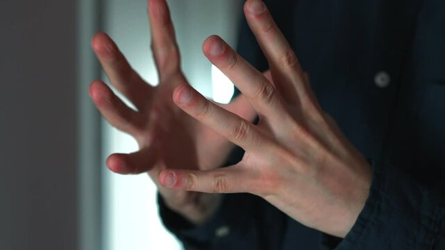 A man clenches his fists in anger.
A man waves his fists.
Behavior of an aggressive person.
A man in a blue shirt is angry and freaking out
