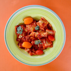 A top view of Beef Ravioli Bolognese with tomatoes and parsley. 