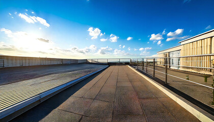 Fototapeta premium 晴れたビルの屋上。コンクリート、手すり、青空のある屋上の風景。Sunny rooftop of a building. Rooftop view with concrete, railings and blue sky.