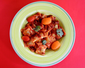 A top view of Beef Ravioli Bolognese with tomatoes and parsley. 