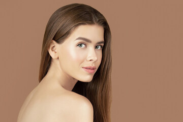 Feminine nude woman with silky skin and long straight hair posing on brown studio background....