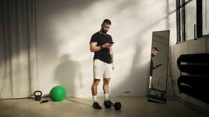 A fitness enthusiast checks their smartphone in a modern gym, committed to health