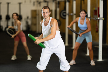 Obraz premium Closeup of athletic sports man standing with plate of barbell in hands in modern fitness studio