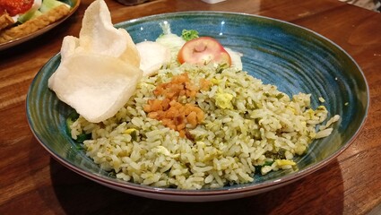 Traditional Indonesian fried rice served with fresh vegetables and savory seasonings on a plate
