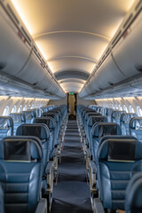 A clean and modern airplane cabin interior, featuring rows of blue leather seats and soft ambient lighting.