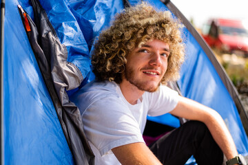 A happy young man enjoying and relaxing in a camping tent.