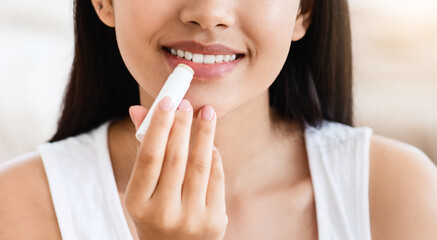 Cropped of asian woman using lipbalm, bedroom interior, panorama with empty space