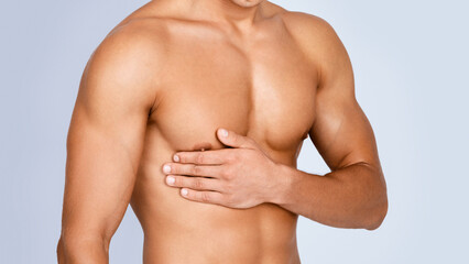 Bodycare Concept. Closeup of unrecognizable strong athletic man with muscular naked torso touching...