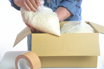 ダンボール箱に白米を梱包する老人