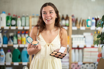 Girl choose product and doubts, pick cheek colors and facial powder cosmetic for allergy sufferers and delicate skin. Client studies product labeling, reads consumer information