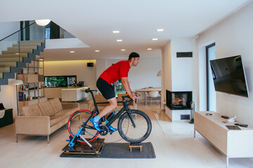 A triathlete riding a triathlon bike on a machine simulation in a modern living room
