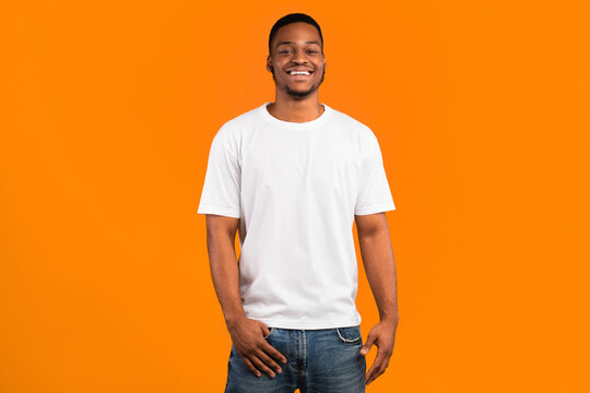 Happy Black Man Smiling To Camera Posing Standing Over Yellow Background, Studio Shot. Good Mood Concept