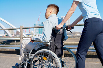 介護士が押す車椅子に乗るシニア男性