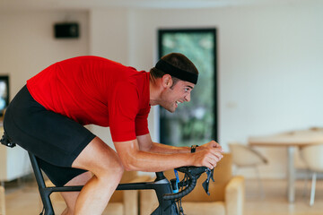 A triathlete riding a triathlon bike on a machine simulation in a modern living room