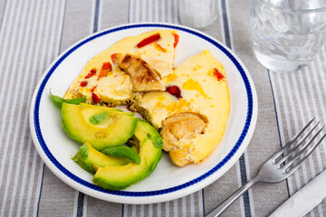 Appetizing chicken omelet with fresh sliced avocado served on plate for breakfast