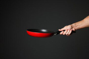 Chef holding frying pan on black background, closeup