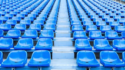 Fototapeta premium A view of rows of blue stadium seats with a central aisle leading upwards in an outdoor setting