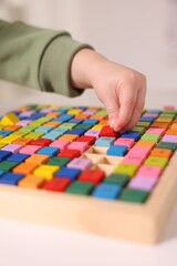 Fototapeta premium Motor skills development. Little boy playing with Times table tray indoors, closeup