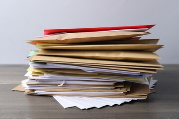 Stack of different paper envelopes on wooden table, closeup. Post office