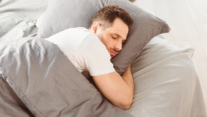 Asleep Man Sleeping Hugging Pillow Lying In Comfortable Bed Resting In Bedroom At Home. Healthy Male Sleep, Recreation And Wellness, Napping Concept. Panorama