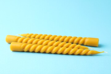 Beautiful beeswax candles on light blue background, closeup