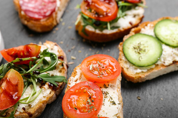 Slate board with tasty sandwiches, closeup