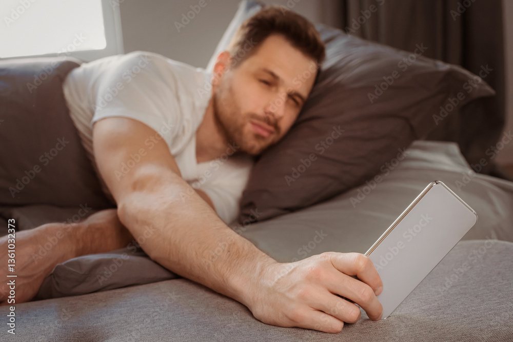 Poster always in touch. man using smartphone waking up early in the morning lying in bed at home. selective
