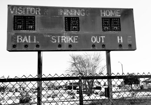 faded retro baseball scoreboard with chipped paint rusty metal vintage numbers cracked surface surrounded by weeds old lights above evoke nostalgia from decades of summer games and crowds cheering - Powered by Adobe