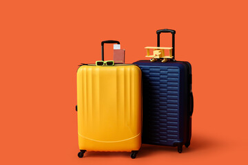 Suitcases with toy airplane, passport and eyeglasses on orange background. Travel concept
