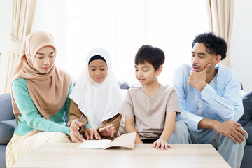 Asian muslim family with father, mother, son, and daughter are sitting in the cozy living room and have a talk together.