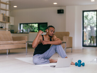 Training At Home. Sporty man doing the training while watching an online tutorial on a laptop,...